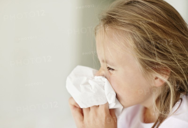 Girl (10-11) blowing nose. Photo : Momentimages