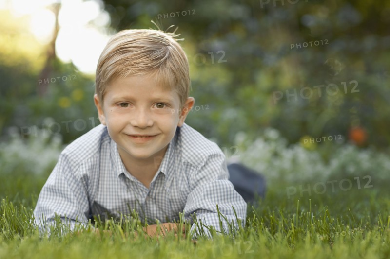 Portrait of boy (6-7) lying on grass. Photo : FBP