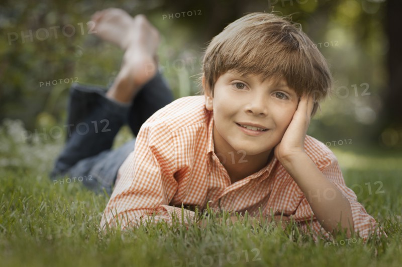 Portrait of boy (8-9) lying on grass. Photo : FBP