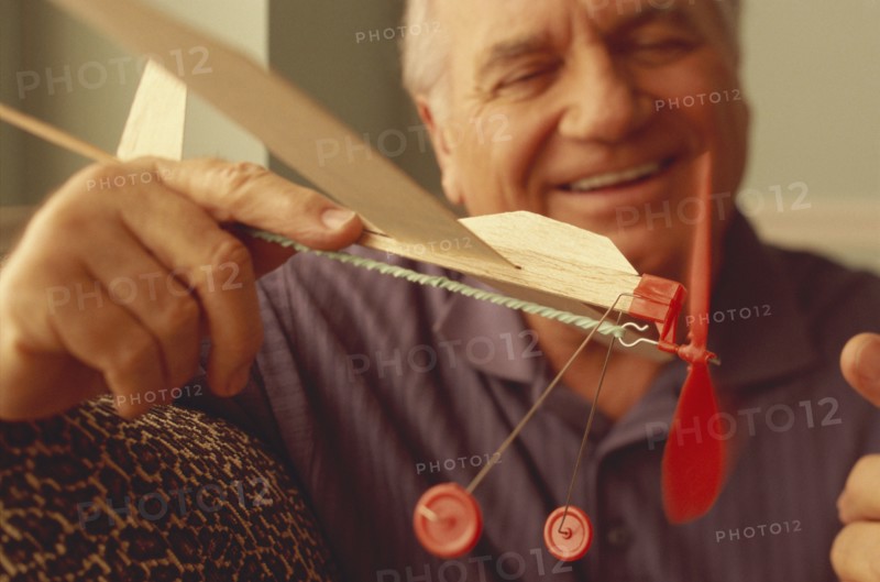 Senior man playing with toy airplane. Photo : Fisher Litwin