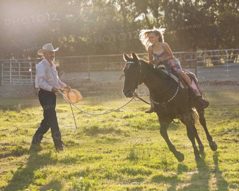 Trainer assisting girl (8-9) riding horse in paddock. Photo : Mike Kemp