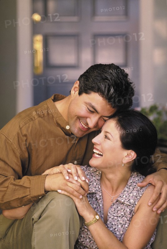 Happy couple sitting in front of their home. Photo : Fisher Litwin