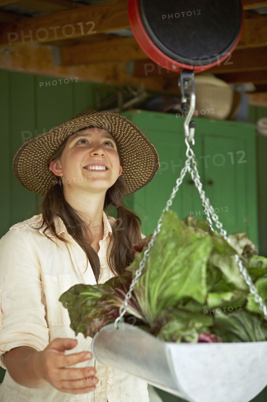 Young woman weighing cabbages. Photo : Shawn O'Connor