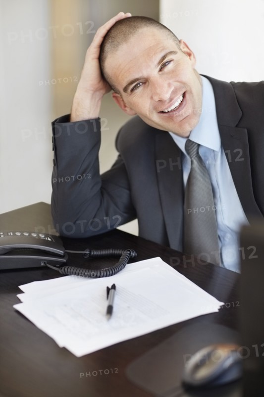 Portrait of cheerful businessman in office environment. Photo : Momentimages