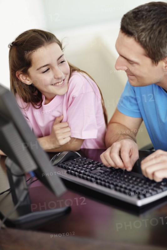 Father with daughter (10-11) playing with computer. Photo : Momentimages