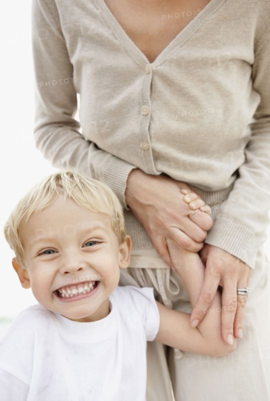 Portrait of boy (4-5) holding mother hand and making face. Photo : Momentimages