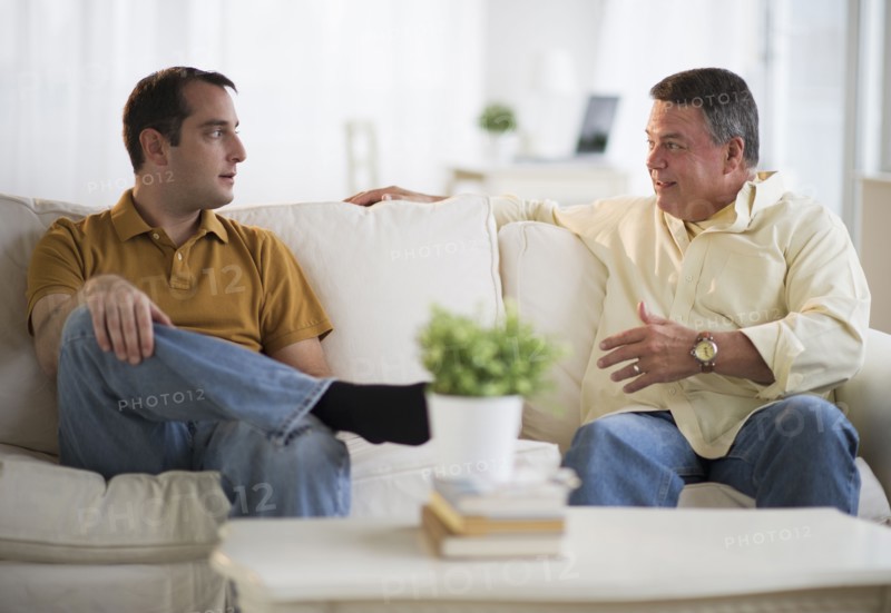 USA, New Jersey, Jersey City, Father and son talking on sofa in living room.