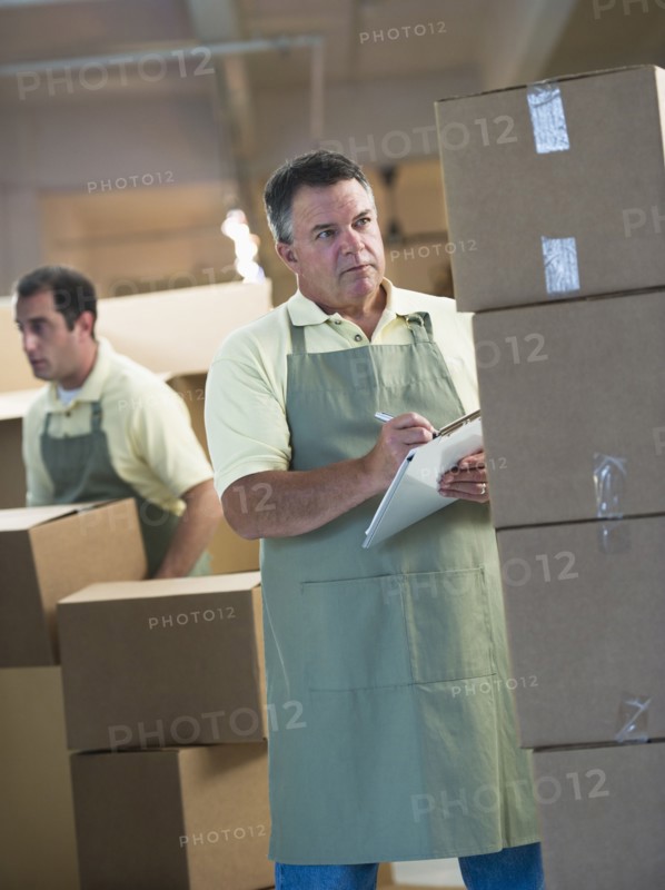 USA, New Jersey, Jersey City, Two male warehouse workers by stacked boxes.