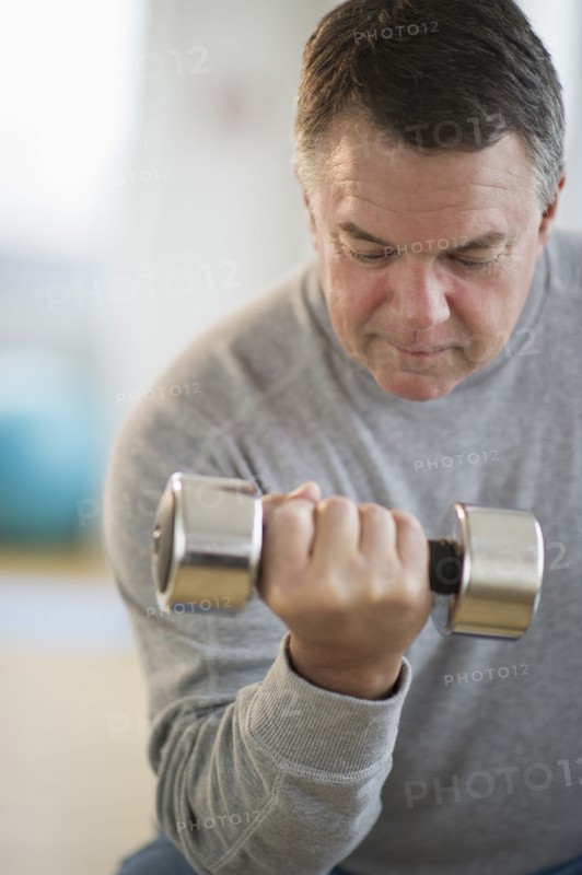 USA, New Jersey, Jersey City, Fitness instructor assisting man using hand weight in gym.