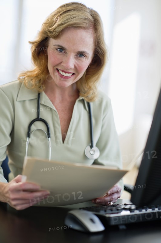 USA, New Jersey, Jersey City, Portrait of female doctor holding medical record in office.