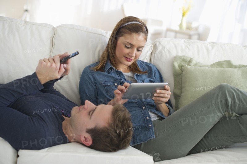 USA, New Jersey, Jersey City, Portrait of young couple relaxing on sofa.