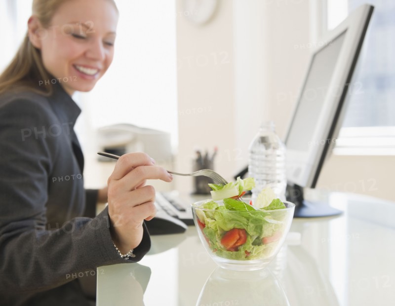 USA, New Jersey, Jersey City, young businesswoman eating salad in office. Photo : Jamie Grill Photography