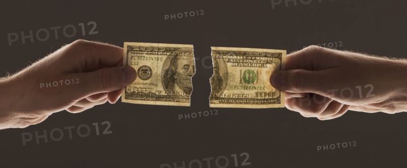 Hands holding torn one hundred dollar bill. Photo : Mike Kemp