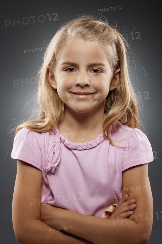 Portrait of girl (8-9) looking at camera with arms crossed, studio shot. Photo : FBP