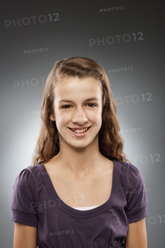 Portrait of girl (12-13) looking at camera and smiling, studio shot. Photo : FBP
