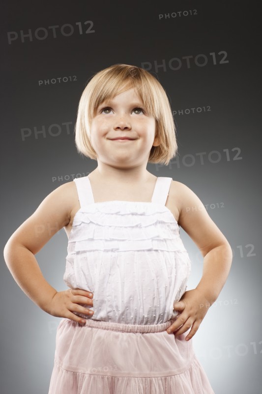 Girl (2-3) with hands on hip and looking up, studio shot. Photo : FBP