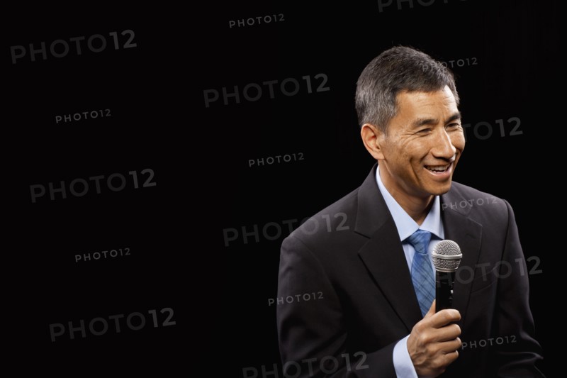 USA, Utah, Provo, Smiling businessman with microphone standing ion stage. Photo : FBP