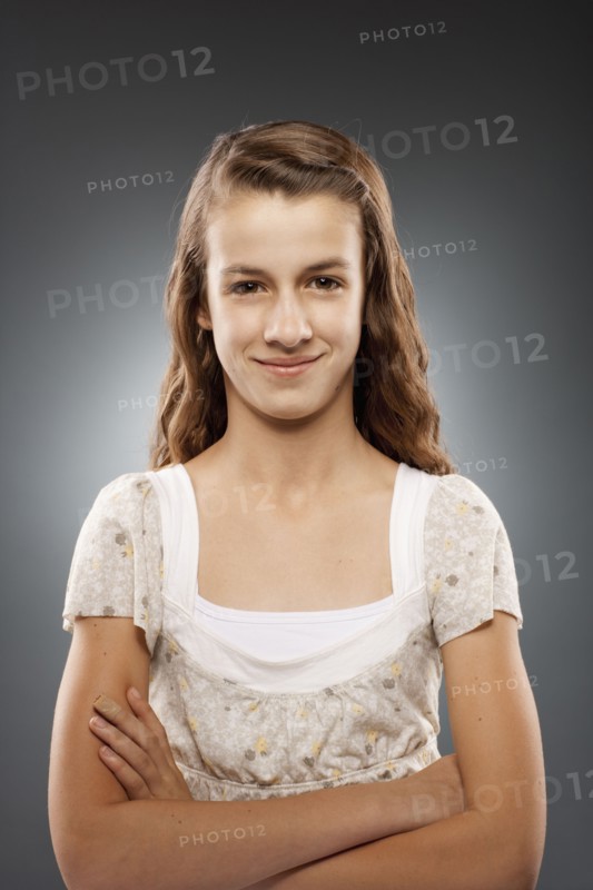 Portrait of girl (12-13) looking at camera with arms crossed, studio shot. Photo : FBP