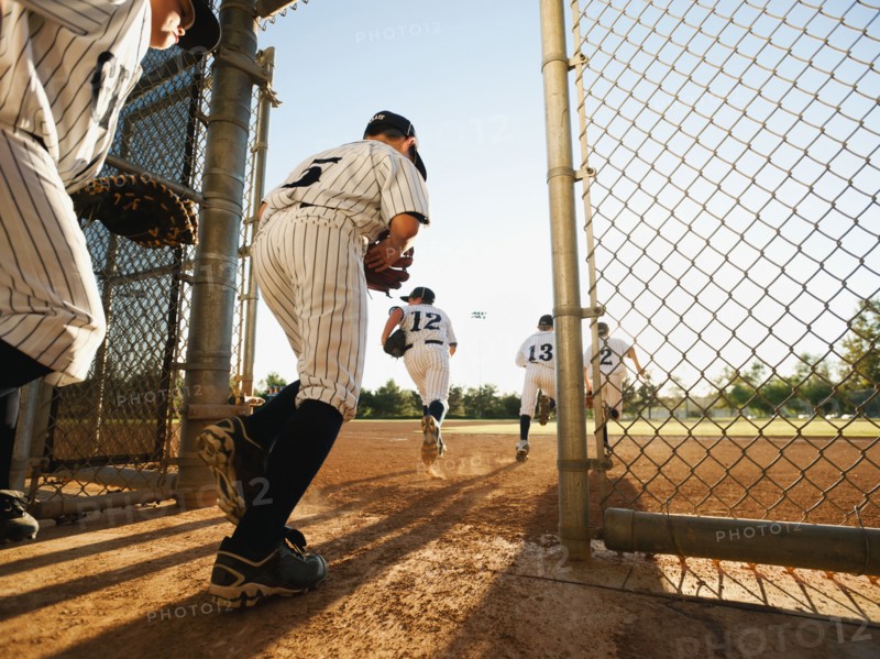 Baseball players (10-11) entering baseball diamond.