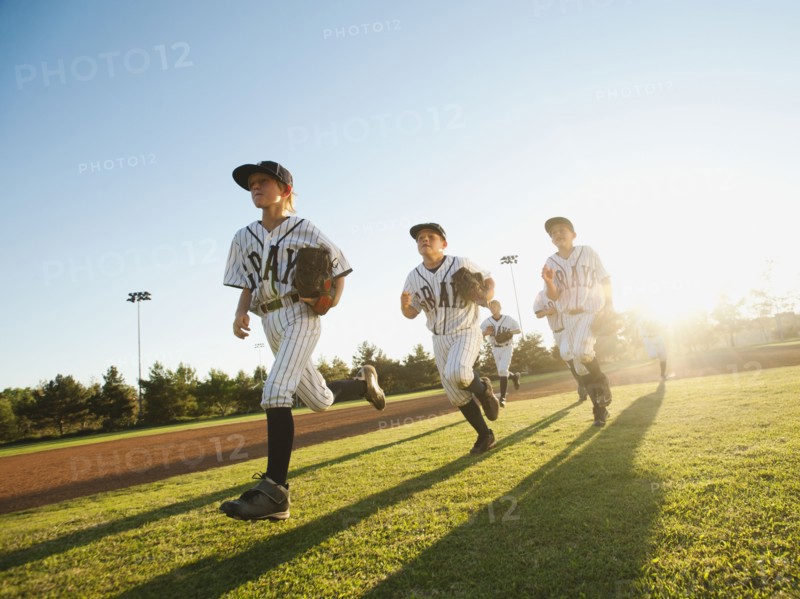 Baseball players (10-11) running on baseball diamond.