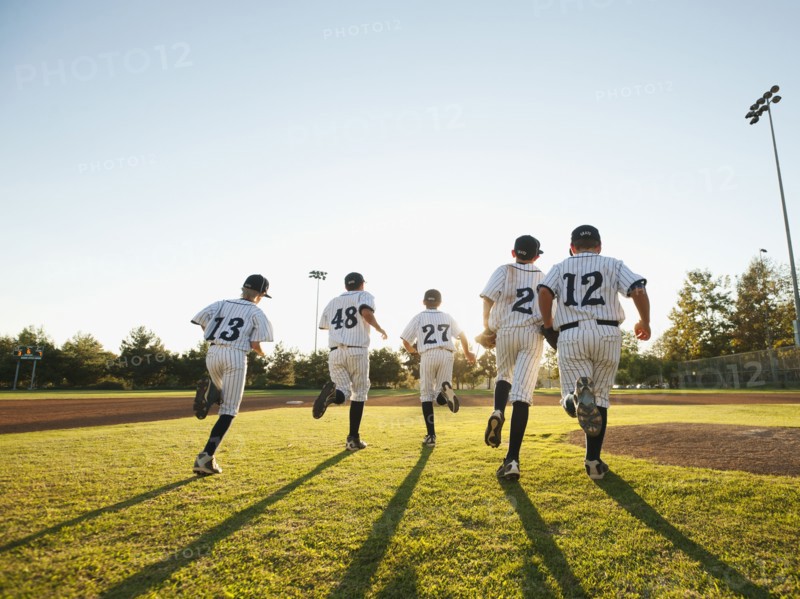 Baseball players (10-11) running on baseball diamond.