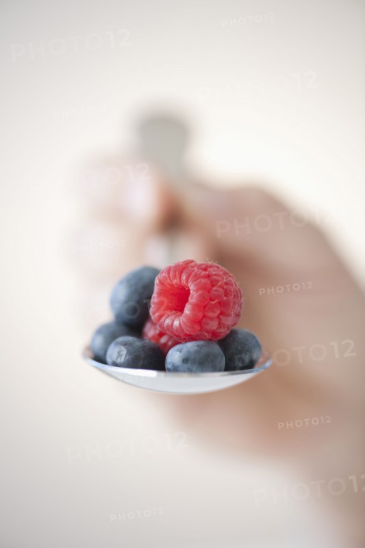 Blueberries and raspberry on spoon.