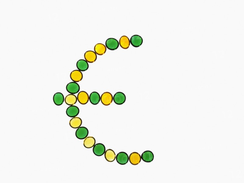 Studio shot of yellow and green glass beads in euro symbol shape. Photo : David Arky