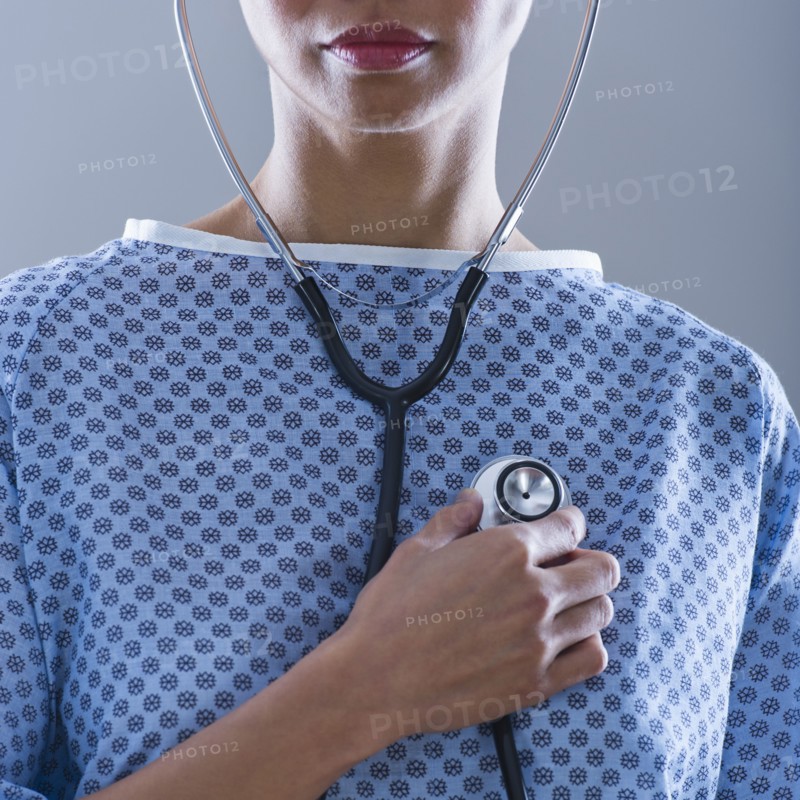 Female patient holding stethoscope to chest.
