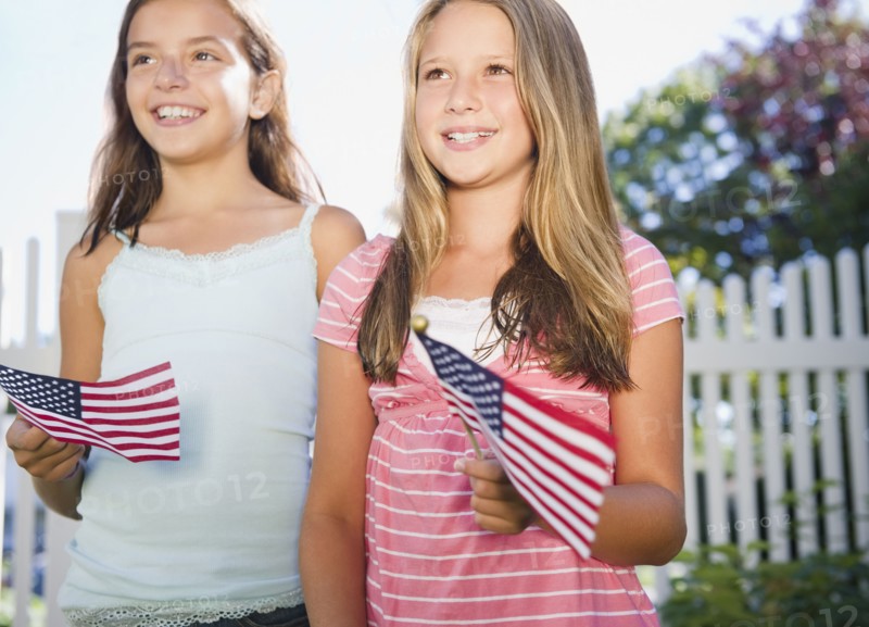 USA, New York, Two girls (10-11, 10-11) playing with American flags. Photo : Jamie Grill Photography