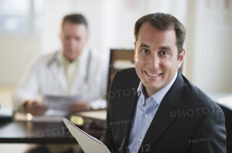 USA, New Jersey, Jersey City, Portrait of male patient holding medical results in office.