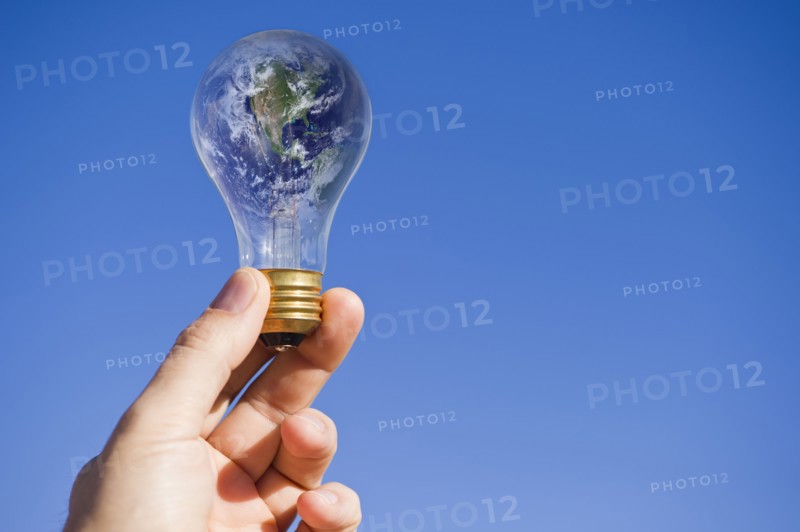 Hand holding lightbulb with globe. Photo : Daniel Grill