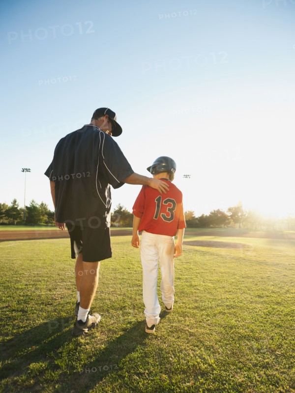 USA, California, Ladera Ranch, man and boy (10-11) walking on baseball field.