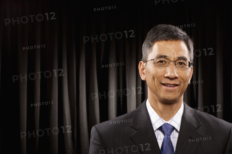 USA, Utah, Provo, Portrait of businessman standing in front of black curtain. Photo : FBP