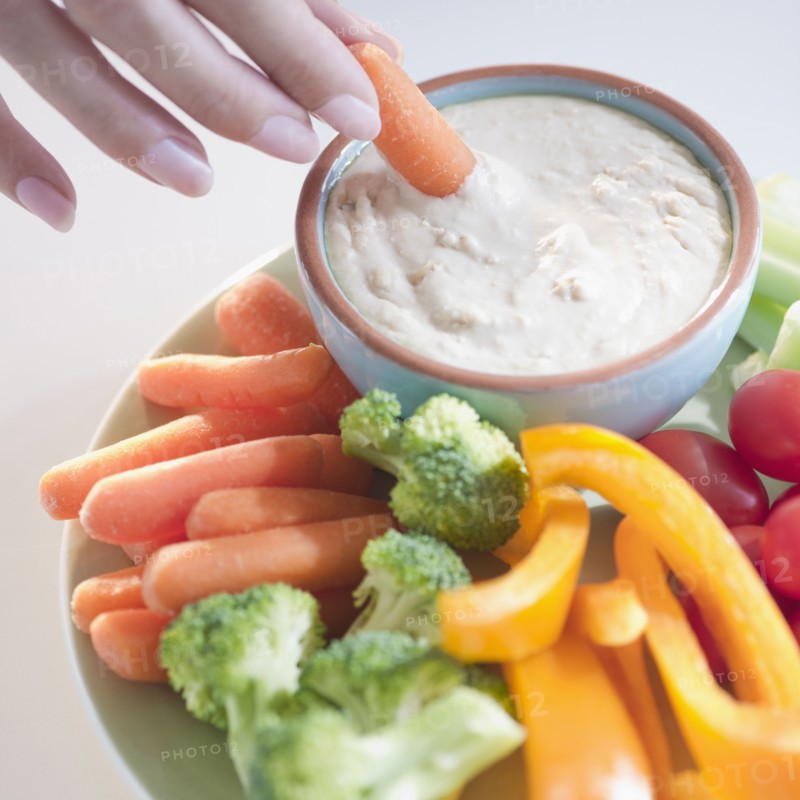 USA, New Jersey, Jersey City, Close-up view of woman hand putting baby carrot into dip. Photo : Jamie Grill Photography