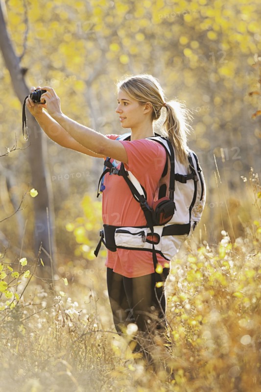 USA, Utah, young woman taking photograph in forest. Photo : Mike Kemp