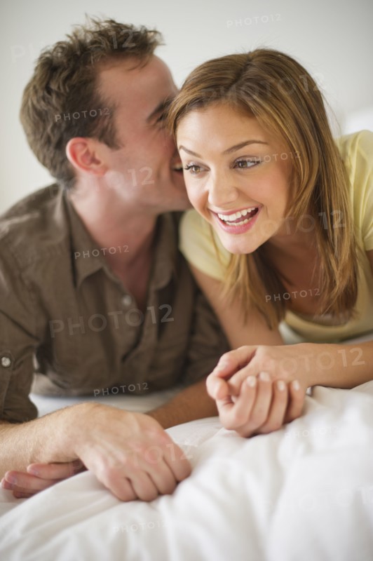 USA, New Jersey, Jersey City, Portrait of young couple lying on bed.