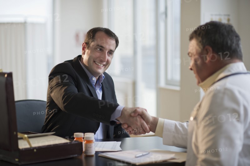 USA, New Jersey, Jersey City, Medical sales representative shaking hands with doctor in office.