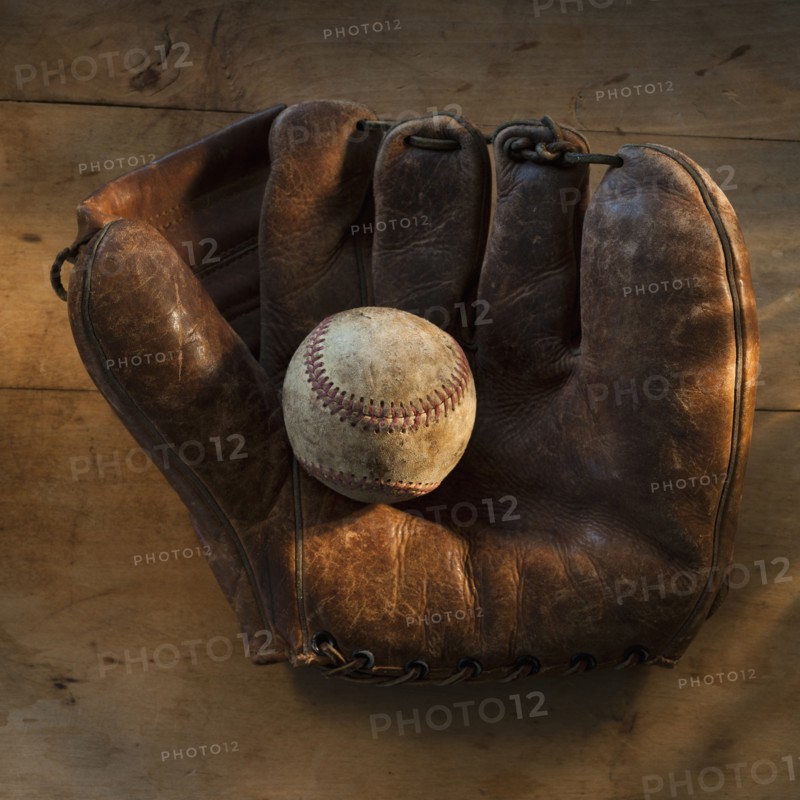 Antique baseball on baseball glove with bat.
