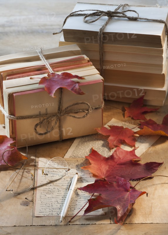 Autumn leaves on letter by books.