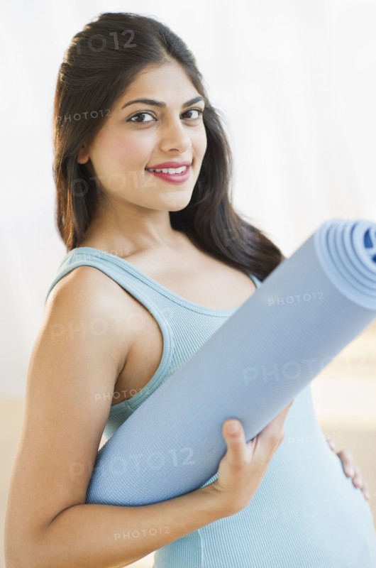 USA, New Jersey, Jersey City, Pregnant young attractive woman with exercising mat. Photo : Daniel Grill