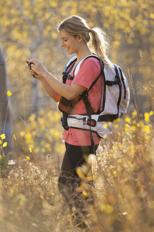 USA, Utah, young woman taking photograph in forest. Photo : Mike Kemp