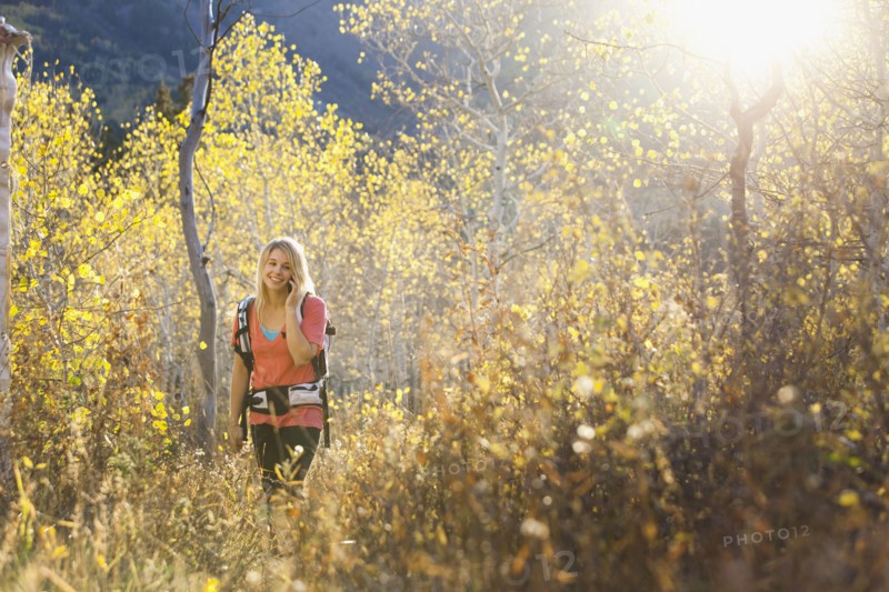 USA, Utah, young woman hiking in forest and talking on mobile phone. Photo : Mike Kemp