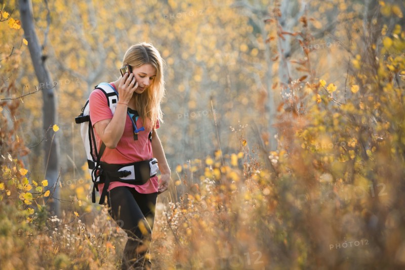 USA, Utah, young woman hiking in forest and talking on mobile phone. Photo : Mike Kemp