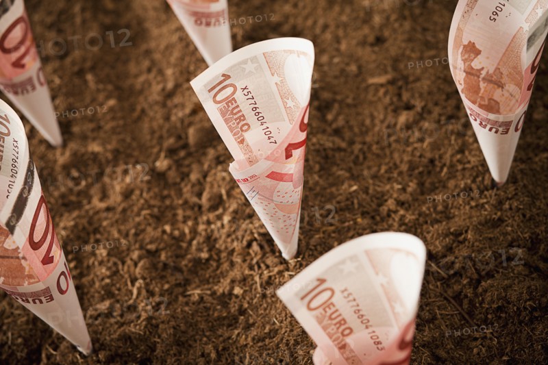 Rolled up ten euro notes stuck in ground. Photo : Mike Kemp