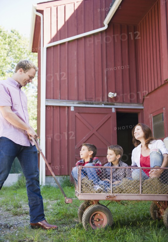USA, New York, Flanders, Father pulling mother and two boys (4-5, 8-9) on trolley. Photo : Jamie Grill Photography