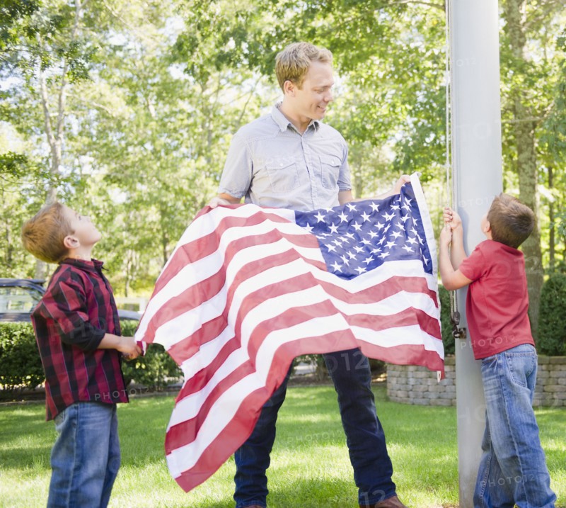 USA, New York, Flanders, Father with two boys (4-5, 8-9) hanging American flag on pole. Photo : Jamie Grill Photography
