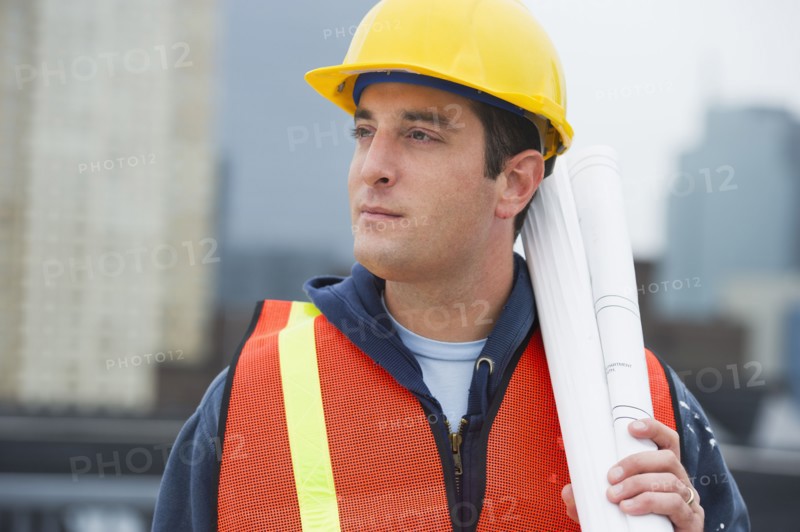 USA, New Jersey, Jersey City, Construction worker holding blueprints on construction site.