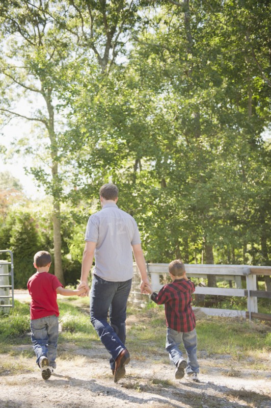 USA, New York, Flanders, Father with two sons (4-5, 8-9) walking in farm. Photo : Jamie Grill Photography