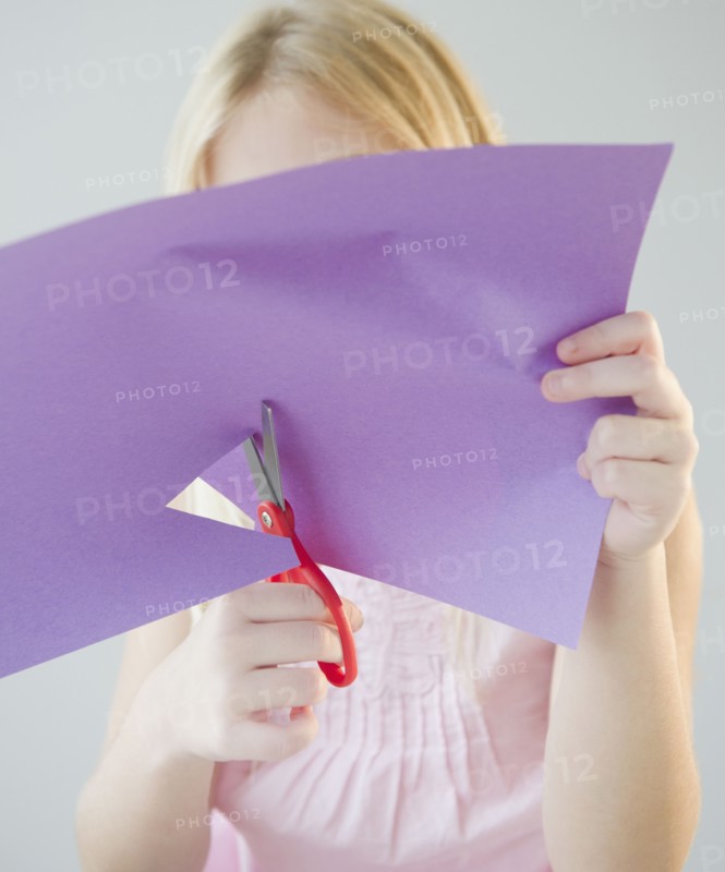 USA, New Jersey, Jersey City, Girl (8-9) cutting star shape in paper. Photo : Jamie Grill Photography