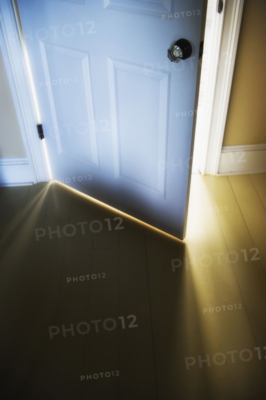 Sunlight shining through open door .